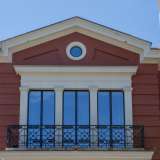 Sul corpo centrale, leggermente aggettante, si aprono invece degli ampi finestroni, di cui quelli superiori dotati di balcone con ringhiera in ferro